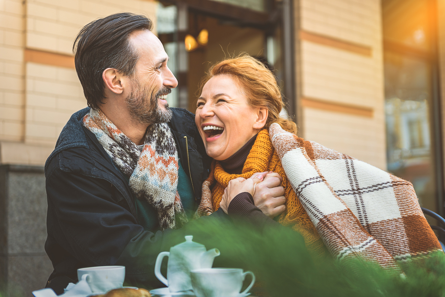happy laughing mature couple wrapped in blanket
