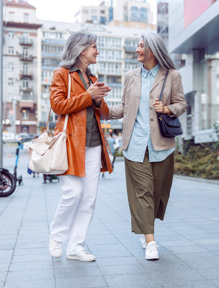 two elegant mature women walking through city